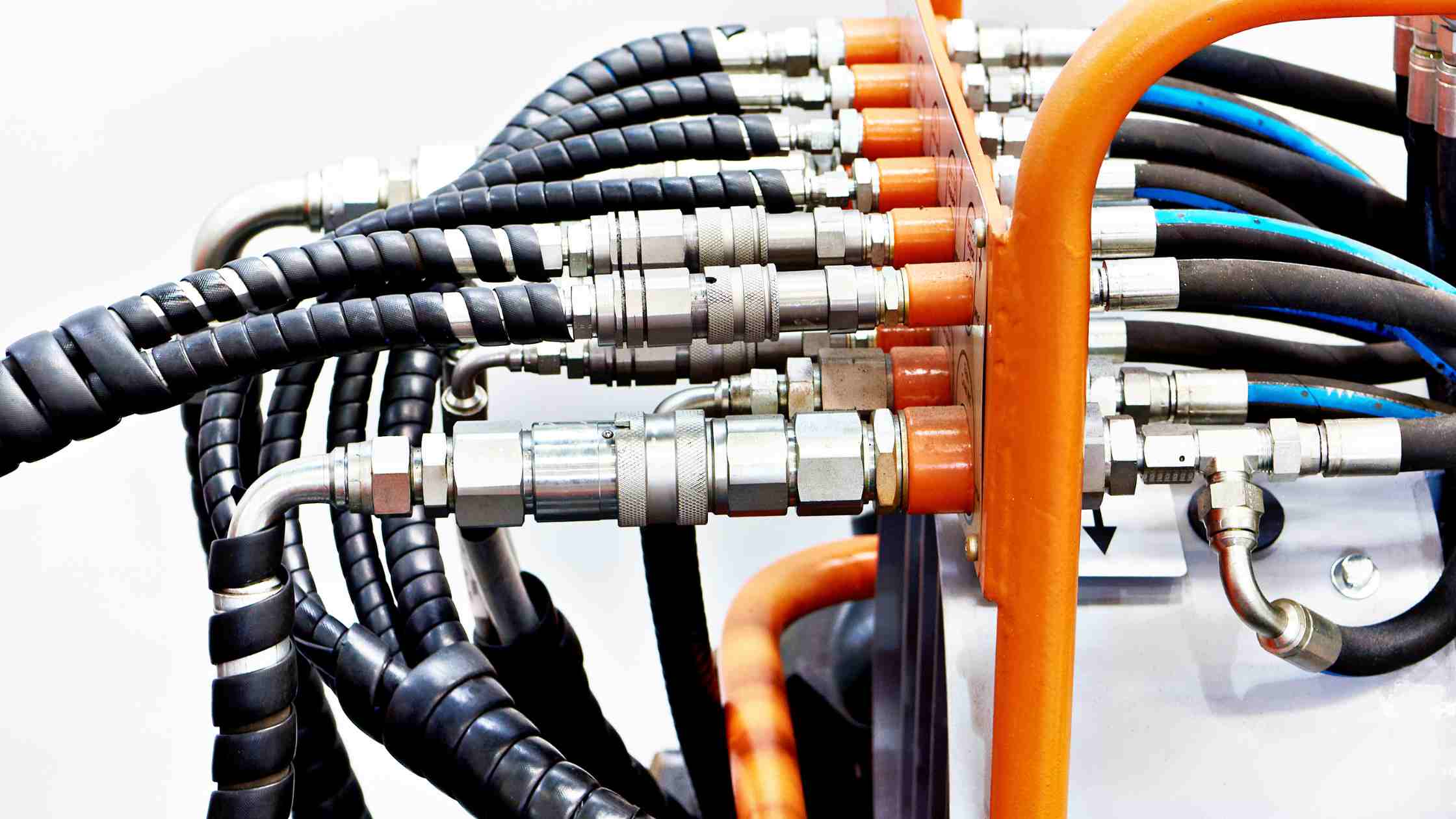Multiple hydraulic hose fittings connected to a hydraulic manifold with high-pressure hoses and metal couplings
